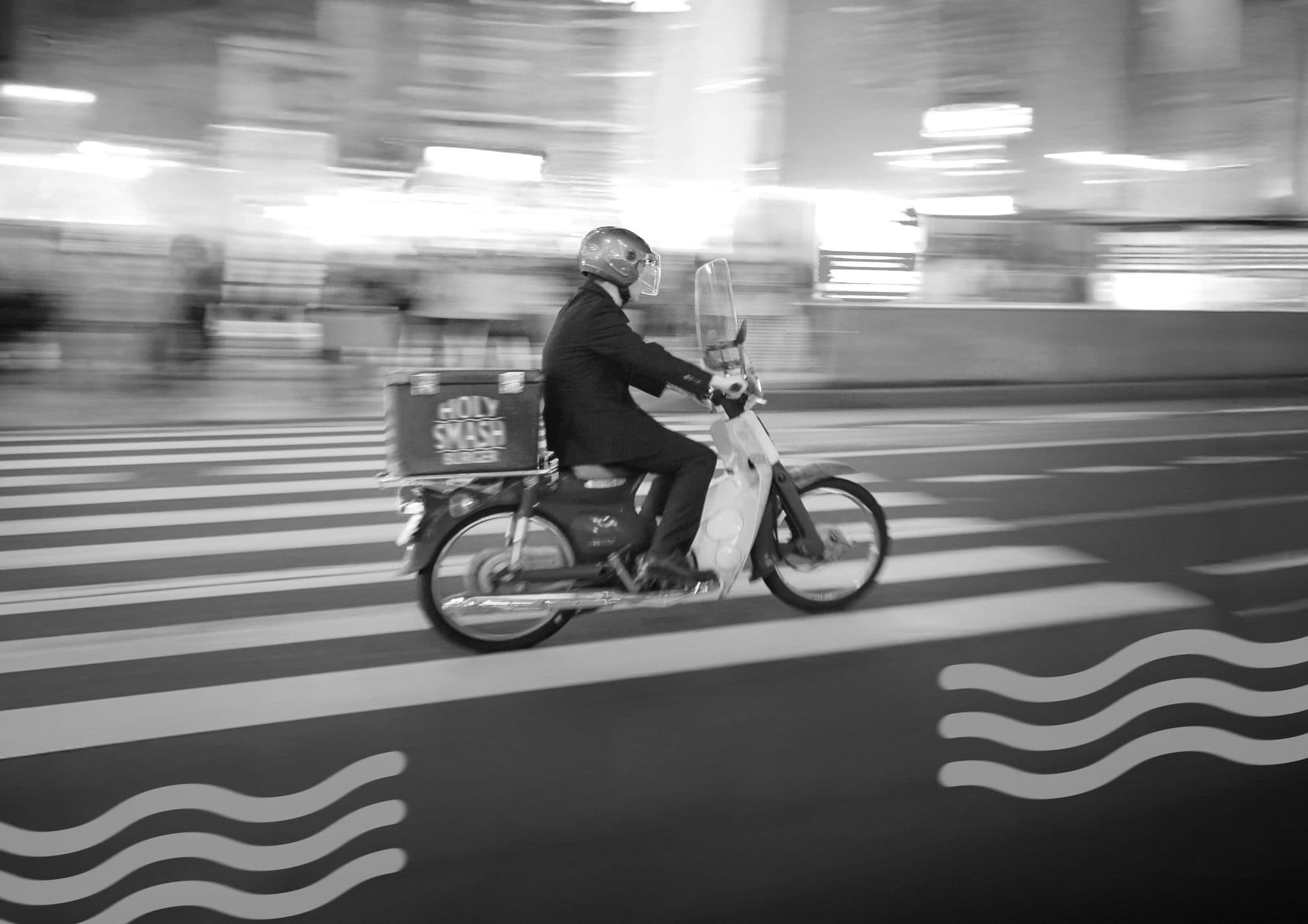 Holy Smash Burger delivery rider on a scooter at night